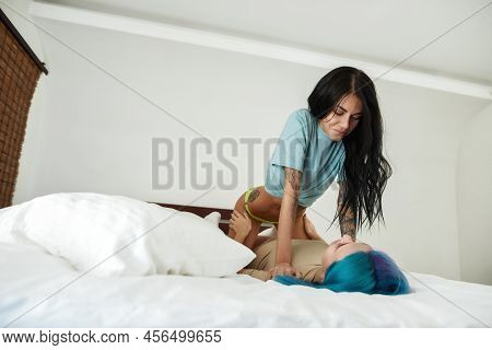 Beautiful Young Caucasian Lesbian Couple Lying, Resting And Looking At Each Other On Bed At Home. Ho