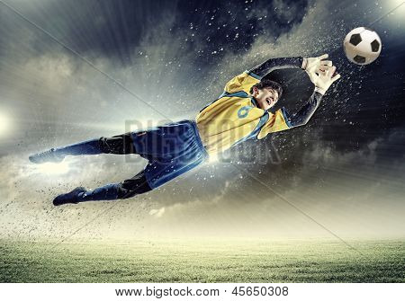 Torwart fängt den Ball. Im Stadion, im Rampenlicht.