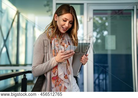 Outdoors Portrait Of Beautiful Young Business, Student Woman Laughing And Using Cell Phone