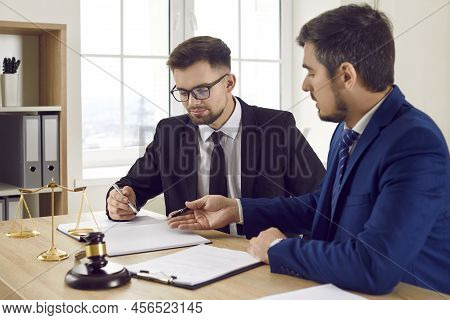 Two Professional Male Lawyers Read Legal Documents And Study Information About Court Case Together.