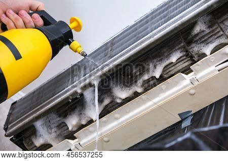 A Man Washes Off A Special Foam For Cleaning Air Conditioners With A Jet Of Water Under Pressure. Sp