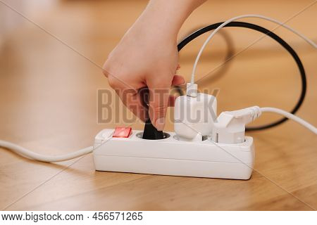 Woman Pluging The Black Wire Into White Extension Cord. Close Up Of Female Hand Put Cabel. Charger