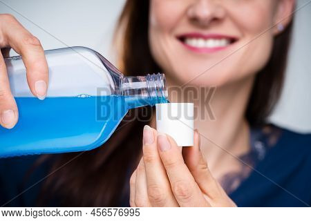 Close-up Of A Woman's Hand Pouring Mouthwash Into Cap