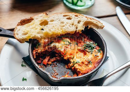 Half Eaten Freshly Made Shakshuka With Tomato, Red Pepper, Feta, Egg, Coriander And Pieces Of Homema