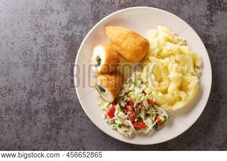 Chicken Kiev Cutlets Served With Salad And Mashed Potatoes Closeup In The Plate On The Table. Horizo