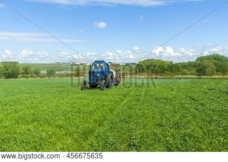 Agricultural Machinery, Tractor And Farmer In Agricultural Fields Of Wheat And Rapeseed And Dramatic
