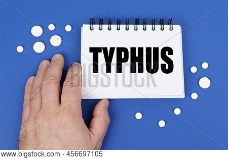 Medical Concept. On The Blue Surface Of The Tablet, A Hand And A Notepad With The Inscription - Typh