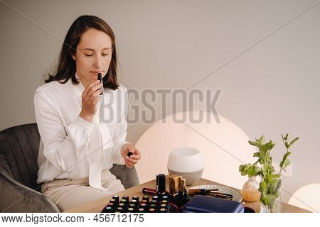 The Aromatherapist Girl Is Sitting In Her Office And Holding A Bottle Of Aromatic Oils. There Are Es