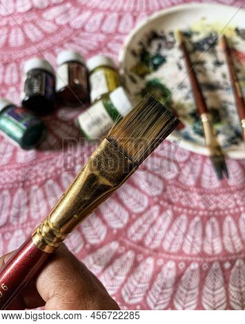 Artists Brushes Or Painting Brushes With Palatte And Colour Bottles In Blurred Background.
