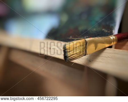 Artists Brush Isolated Near Canvas Painting On Wooden Tripod Easel. Selective Focus With Blurred Bac