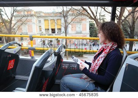 Ung smuk kvinde i turistbussen nær Prado lytter tour program i Madrid, Spanien.