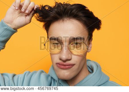 A Close Portrait Of A Funny Man Standing On An Orange Background In Bright Sunglasses Looking At The