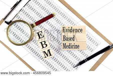 Ebm - Evidence-based Medicine Text On A Wooden Block On Chart Background