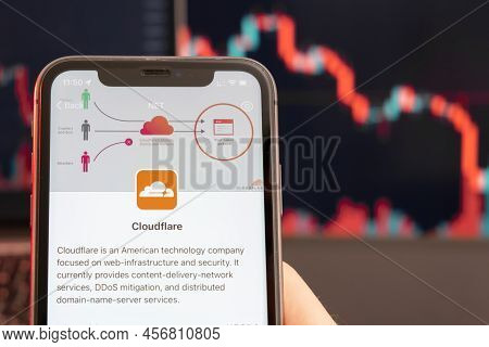 Cloudflare Stock Price Downtrend With Red Graphs On The Background. Man Hands Holding A Smartphone W