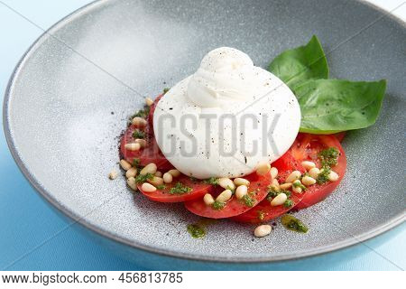 Buratta Cheese And Tomatoes In A Bowl. Decorated With Pine Nuts. Selective Focus.