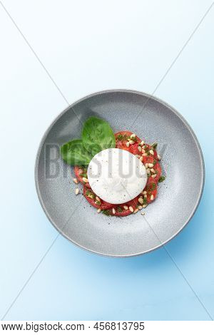 Buratta Cheese And Tomatoes In A Bowl. Decorated With Pine Nuts. Selective Focus.