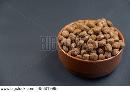 Bowl Of Dog Food Against A Gray Background. Round Brown Pellets In A Ceramic Bowl. Food For Neutered