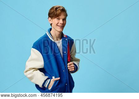 A Handsome Happy Guy Student In A Fashionable Bomber Jacket And With A Backpack On His Shoulder Stan