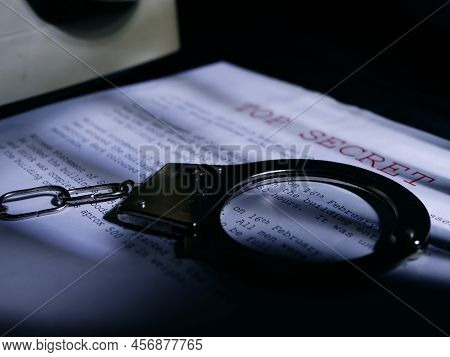 Handcuffs On Top Secret Document In Dark Room