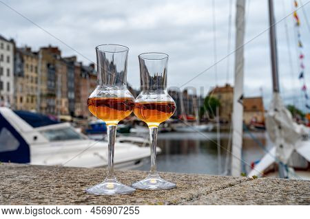 Tasting Of Apple Calvados Drink In Old Honfleur Harbour With Boats And Old Houses On Background, Nor