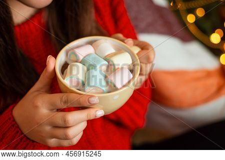 Close-up Shot Of Cup With Cocoa And Marshmello In Hands Of Young Brunette Woman In Red Knitted Sweat
