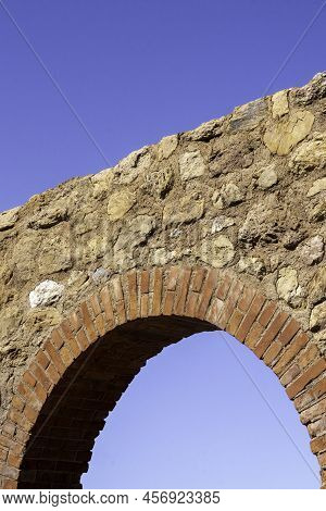 Antique, Old Monument Ruin Arch Architecture Made With Rocks And Bricks With Blue Sky In The Backgro