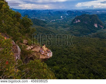 Dragon Crest Mountain Krabi Thailand, A Young Traveler Sits On A Rock That Overhangs The Abyss, With