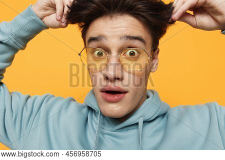 A Close Portrait Of A Funny Man Standing On An Orange Background In Bright Sunglasses Looking At The