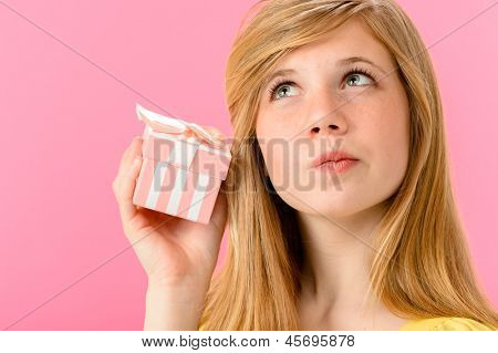 Ragazza curiosa tenendo chiusi presenti isolato su sfondo rosa