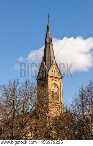 Spire Of Torņakalns Church, Riga, Latvia. Vertical Photo Of Lutheran Basilica White Cloud And Blue S