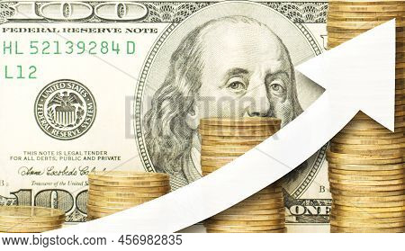 Close Up Photo Of Golden Coins With White Arrow Showing Upward Direction Against A One Hundred Us Do