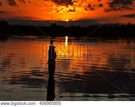 Fishing At Sunset. Catching Predatory Fish On Spinning. Sunset Colors On The Water Surface, Sunny Pa