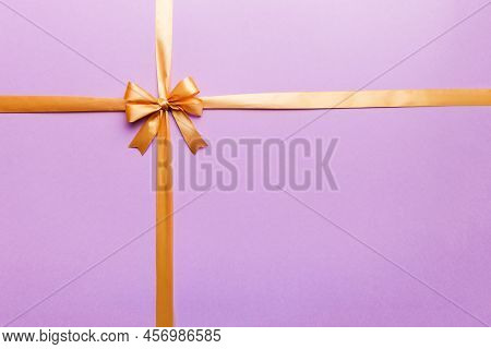 Top View Of Gold Ribbon Rolled And Yellowbow Isolated On Colored Background. Flat Lay With Copy Spac