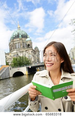 Tourist woman on boat tour Berlin, Germany having fun smiling happy while enjoying mini cruise reading guidebook. Europe travel vacation holiday concept. Multiracial Asian Caucasian woman.