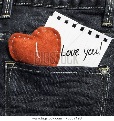 I Love You written on a peace of paper and a heart on a jeans background