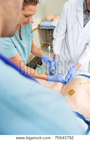 High angle view of nurse and doctor adjusting endotracheal tube in dummy patient's mouth at hospital