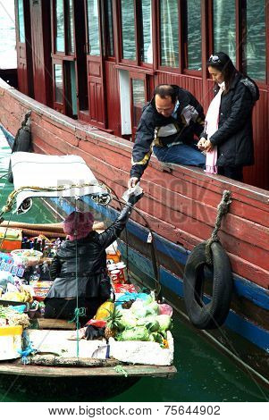 Vietnamese woman selling goods and snack on her boat near tourist argosy.