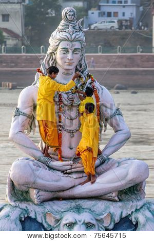 RISHIKESH, INDIA - NOVEMBER 13, 2012: Servants decorate large statue of Hindu Lord Shiva with flowers for the Ganga Aarti ceremony on November 13, 2012 in Rishikesh, India.