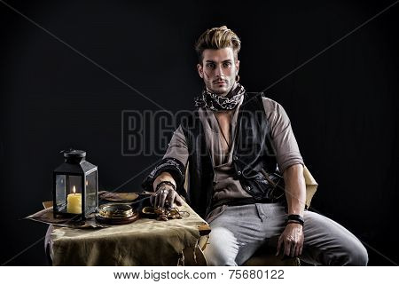 Good Looking Young Man In Pirate Fashion Outfit Sitting Next To Table
