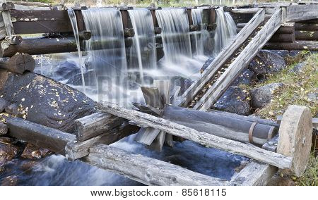 A grindstone connected to water power in an old wooden construction.