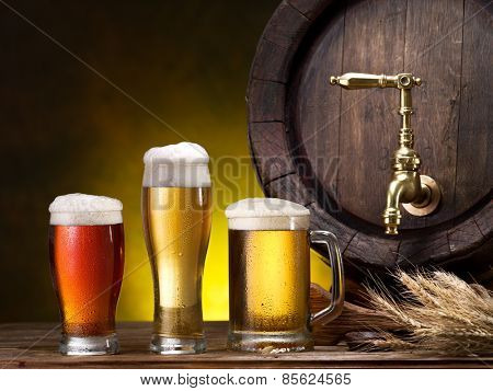 Still life: old wooden pin of beer, glass of beer and wheat on the table in the cellar.