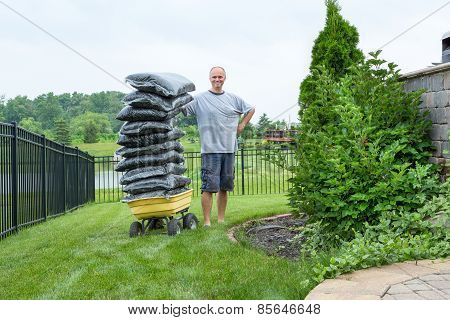 Man Standing Beside A Wagon With Bagged Mulch