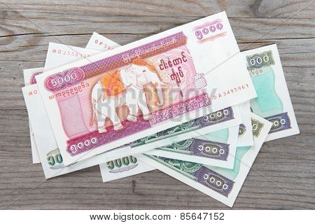 Myanmar kyat bank notes on wooden table, overhead view.