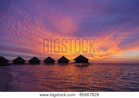 Sunset in the Maldives with a view of the lagoon, beach and bungalows