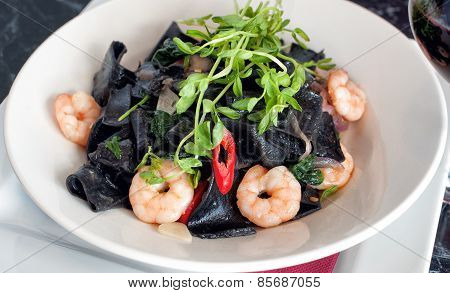 Plate of squid ink pasta and prawns