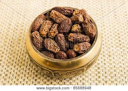 Macro view of dried dates kept in a bowl under a plain background