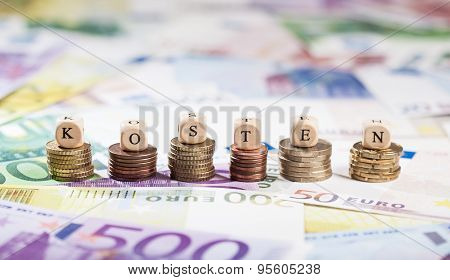 German Word Kosten On Coin Stacks, Cash Background
