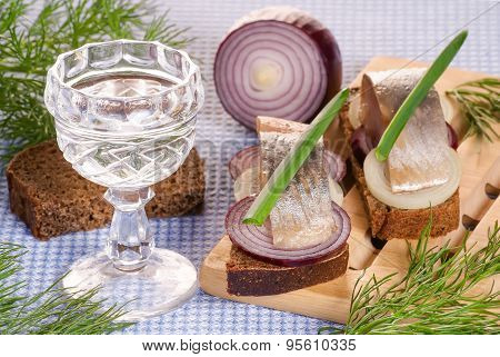 The Pieces Of Salted Herring On Rye Bread With Slices Of Red Onion Decorated Fresh Green And The Gla
