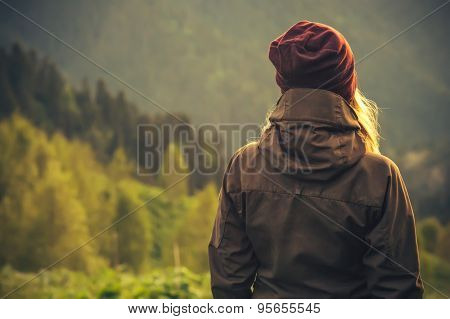 Young Woman standing alone outdoor with wild forest mountains on background