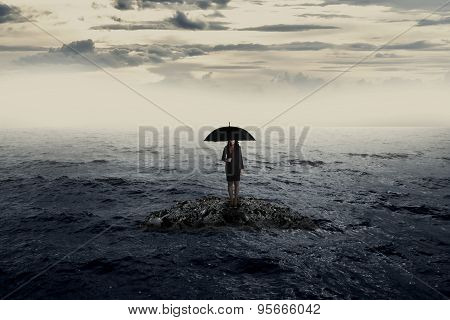 Woman With Umbrella Standing On The Rock In The Middle Of The Sea